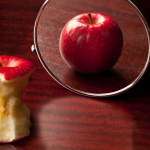 eaten apple looking in the mirror signifying body images issues