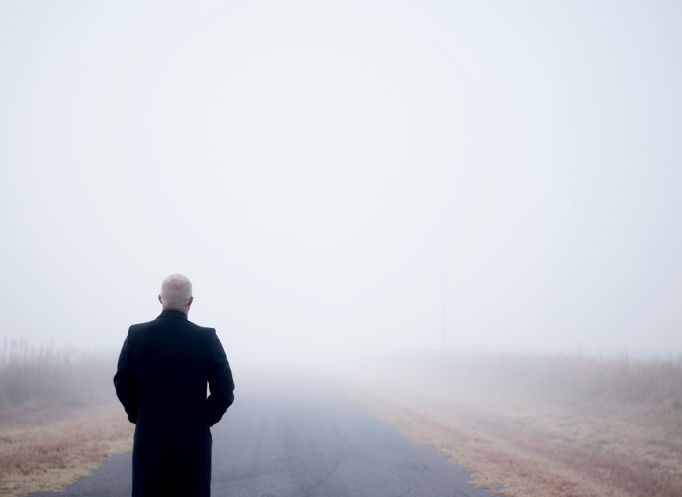 Lonely man walking down an empty road in grief