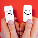 Two dominoes with a smile and a frown to represent mood tracking