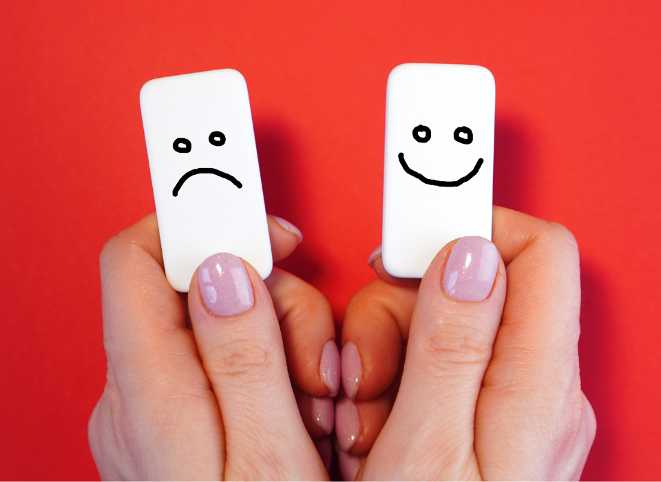 Two dominoes with a smile and a frown to represent mood tracking