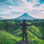 woman standing with arms spread on a hill