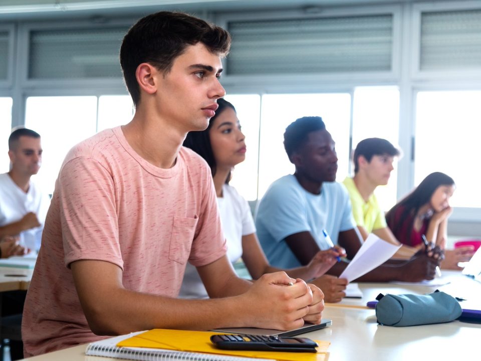 White high school teen male with his classmate paying attention to the teacher