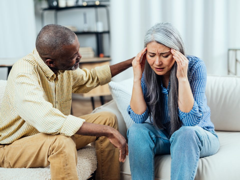 Older woman suffering from social anxiety being comforted by her husband