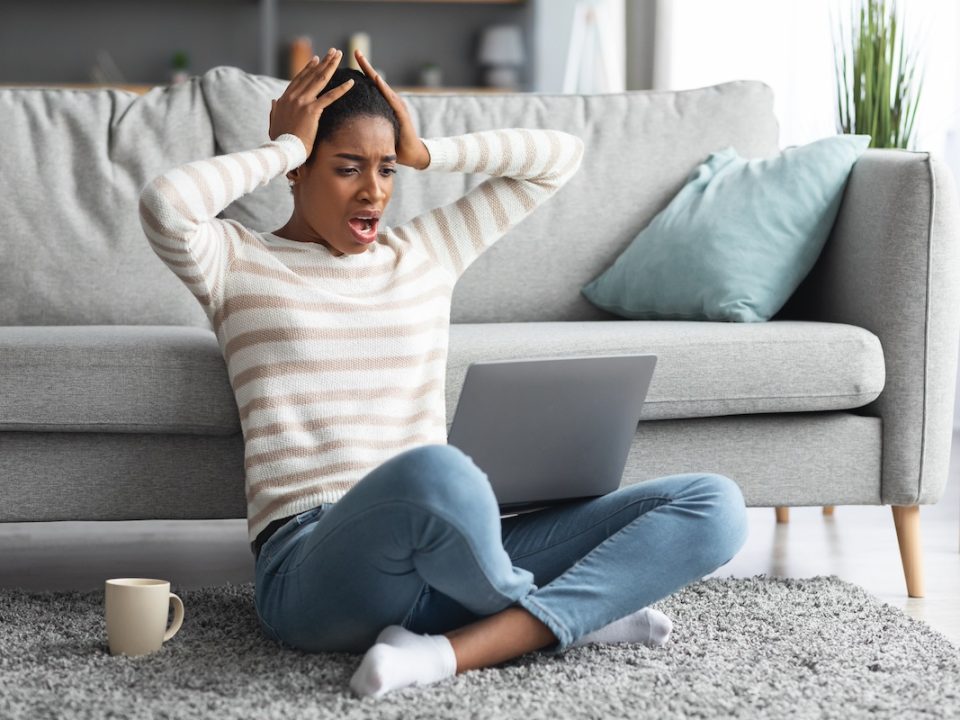 Woman sitting on the floor stressed online shopping during the holidays