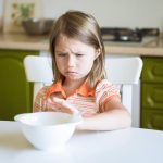 Female child pushing a bowl away dealing with arfid