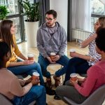 Mixed group of people partaking in a group counseling session.