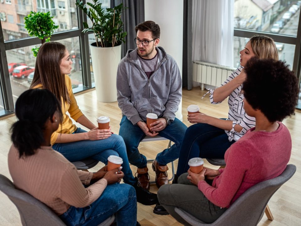 Mixed group of people partaking in a group counseling session.