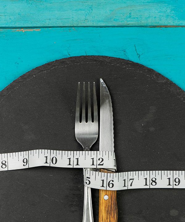 knife and fork on a plate wrapped by measuring tape