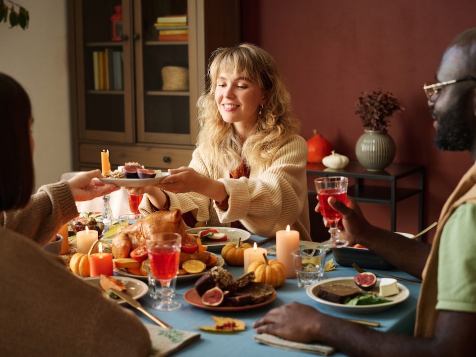 Young adult woman sitting at a table during Thanksgiving practicing mindful eating to avoid binge eating