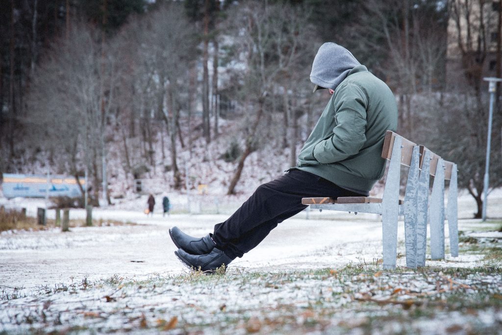 Man sitting alone on a bench in Winter suffering from seasonal depression