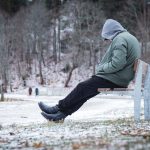 Man sitting alone on a bench in Winter suffering from seasonal depression