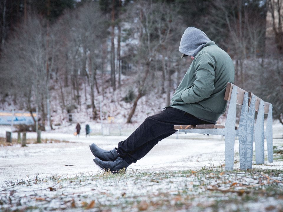 Man sitting alone on a bench in Winter suffering from seasonal depression