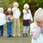 Child hiding her face while being bullied