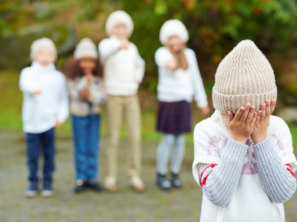 Child hiding her face while being bullied