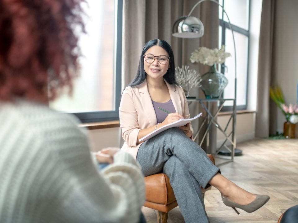 Therapist sitting with female client in a modern room