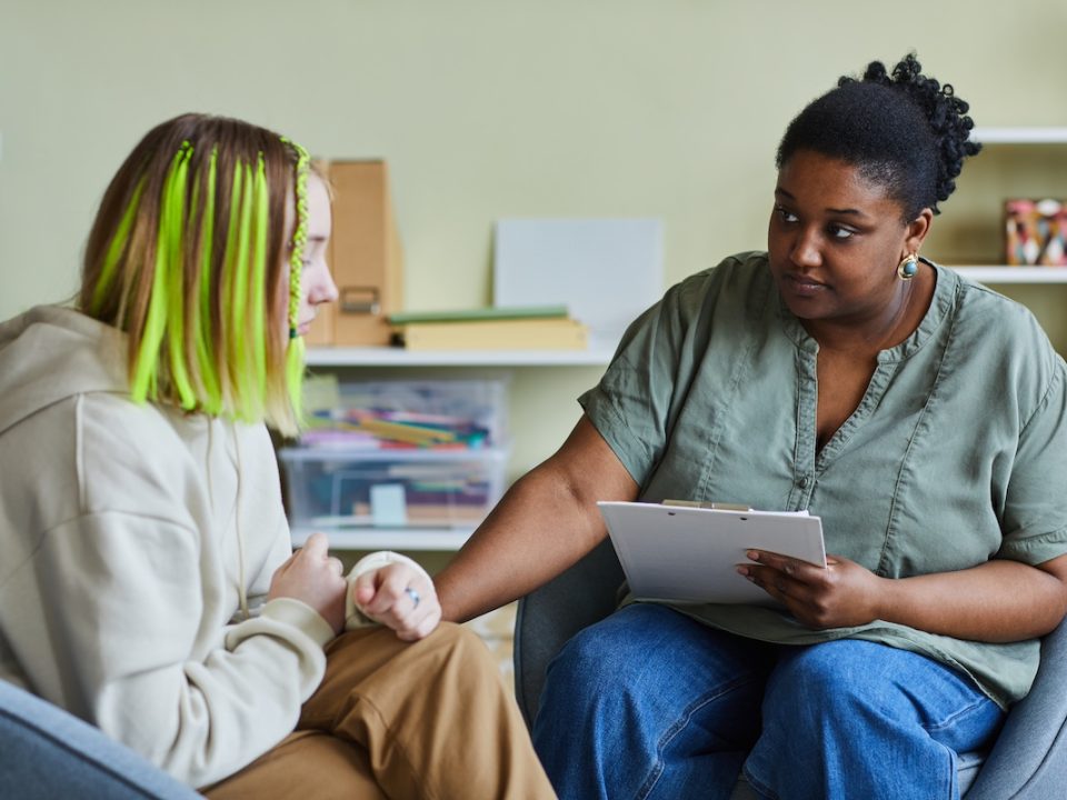 Teenage girl sitting with a therapist discussing her seasonal depression