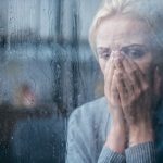 Depressed adult woman staring out a rainy window