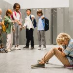 child sitting and crying as classmates name call him