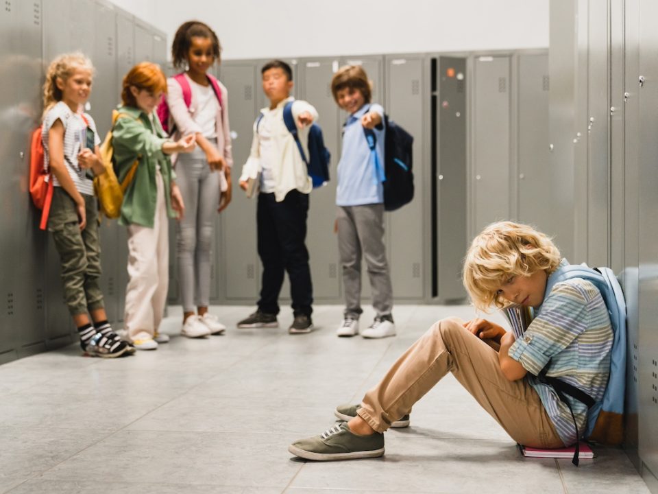 child sitting and crying as classmates name call him