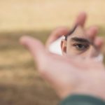 man looking at himself in a tiny mirror contemplating self-harm