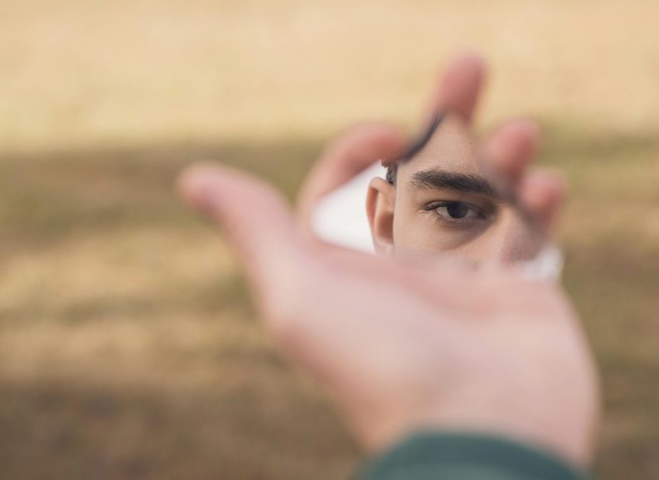 man looking at himself in a tiny mirror contemplating self-harm