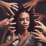 Hands reaching out at a woman's face who is suffering from trauma