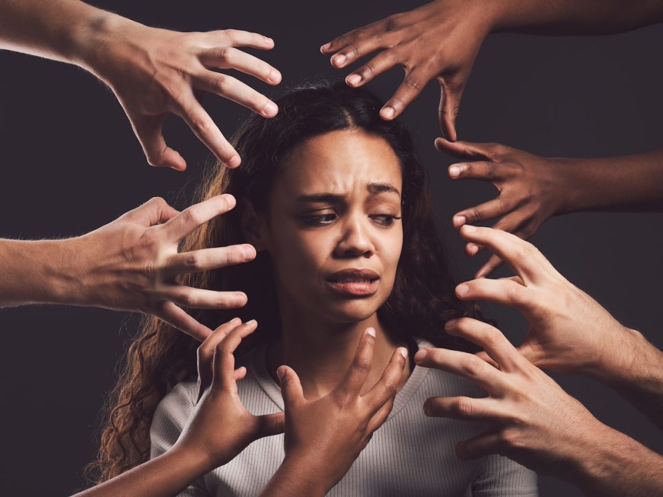 Hands reaching out at a woman's face who is suffering from trauma