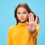 Young woman standing with her hand out as a symbol to avoid binge eating