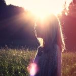 young adult woman standing in a sunny field hopeful about mental health